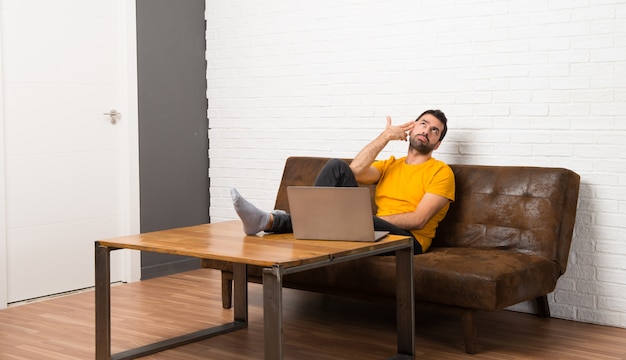 Man met zijn laptop in een kamer met problemen met het maken van zelfmoord gebaar