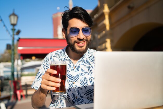 Man met zijn laptop tijdens het drinken van bier.