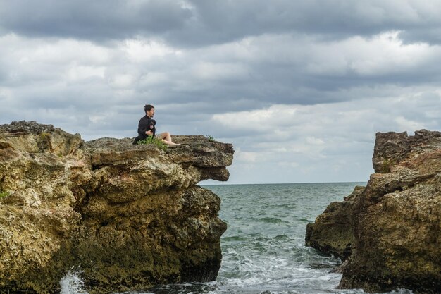 man met zijn puppy zittend in een baai kijkend naar de zee