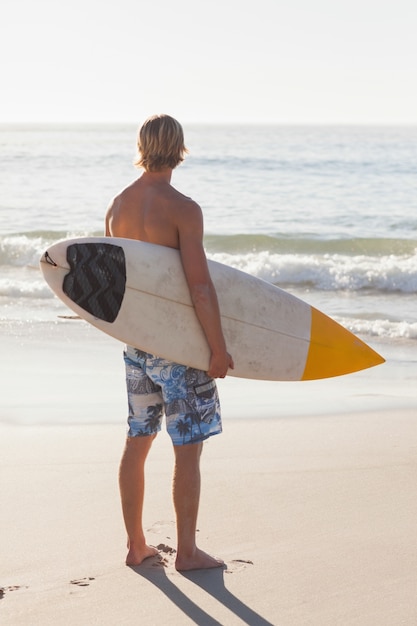 Man met zijn surfplank op het strand