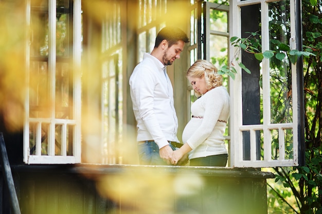 Man met zijn zwangere vrouw op de veranda van het huis