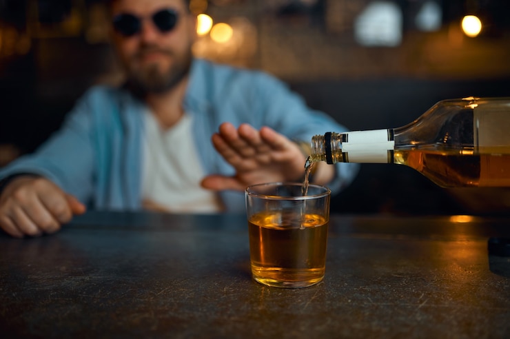 Foto man met zonnebril weigert alcohol te drinken aan de balie in de bar. een mannelijke persoon rust in de kroeg, menselijke emoties, vrijetijdsactiviteiten, nachtleven