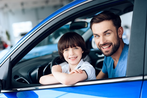 Man met zoon zitten aan het stuur van de nieuwe auto.