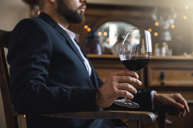 Man met zwart pak met een glas rode wijn