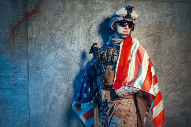 Man military outfit a mercenary soldier in modern times with US flag in studio