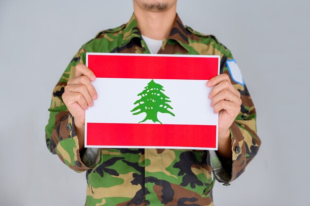 man in a Military shirt holding the flag of Lebanon.