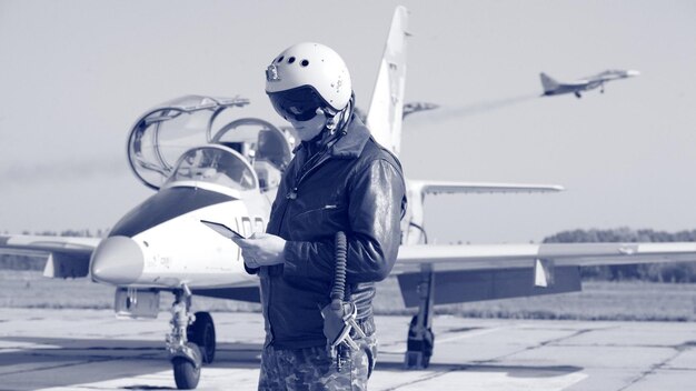 Photo a man in a military uniform stands next to a fighter jet