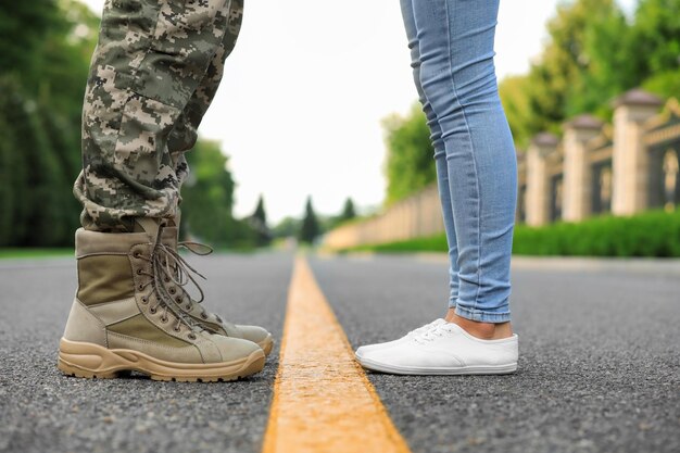 Man in military uniform and young woman separated by yellow line on road closeup