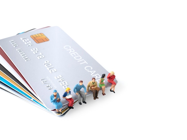 Foto la figura in miniatura dell'uomo si siede sulla pila di carte di credito per spendere soldi dal concetto di carta di credito