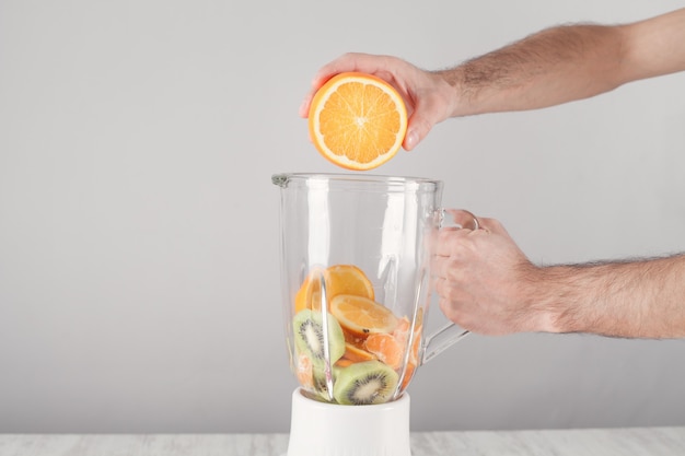 Man mixing fruits with electric blender.