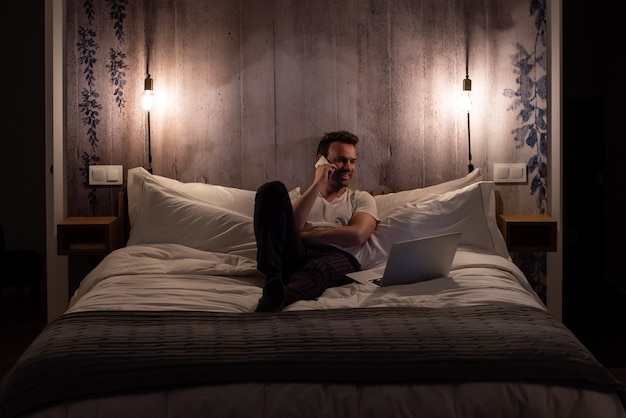 Man on the mobile phone lying down in bed