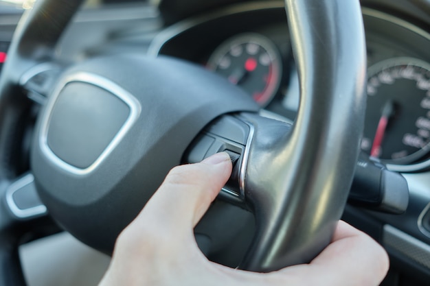 Photo a man in a modern car. turns a hand with a disk with a volume level of music.