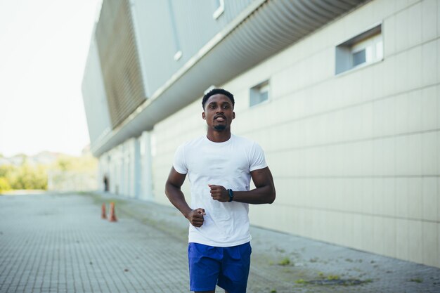 Man on morning run, young african american athlete running near stadium