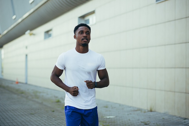 朝のランニングの男、スタジアムの近くを走っている若いアフリカ系アメリカ人アスリート