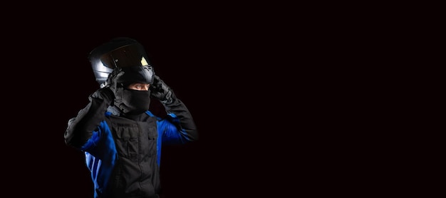 man in a motorcycle helmet in an outfit on a dark studio background.