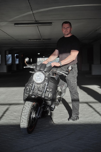 A man and motorcycle in underground parking garage