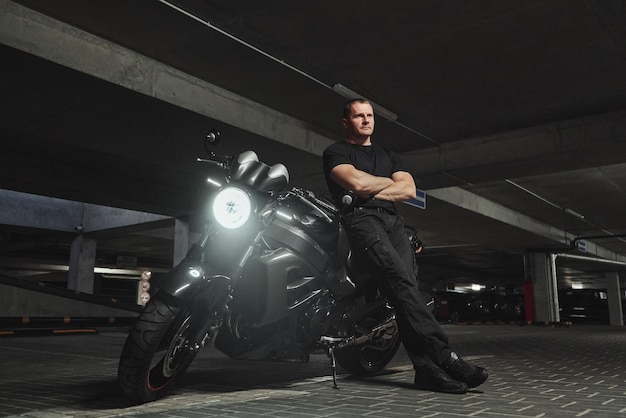 A man and motorcycle in underground parking garage