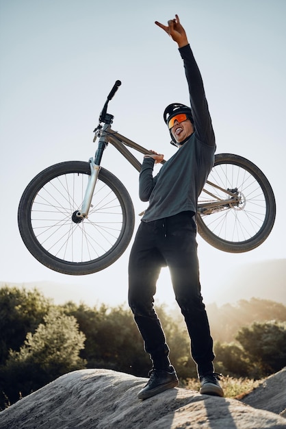 Photo man mountain and bike celebrate happy and excited after reaching summit in training cyclist bicycle and rock in nature lift hand and success in sport adventure for fitness on hill in argentina