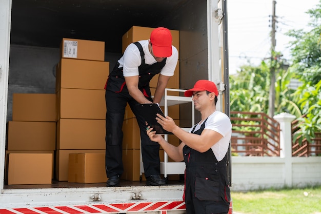 Работник-перевозчик проверяет списки в буфере обмена во время разгрузки картонных коробок из грузовика