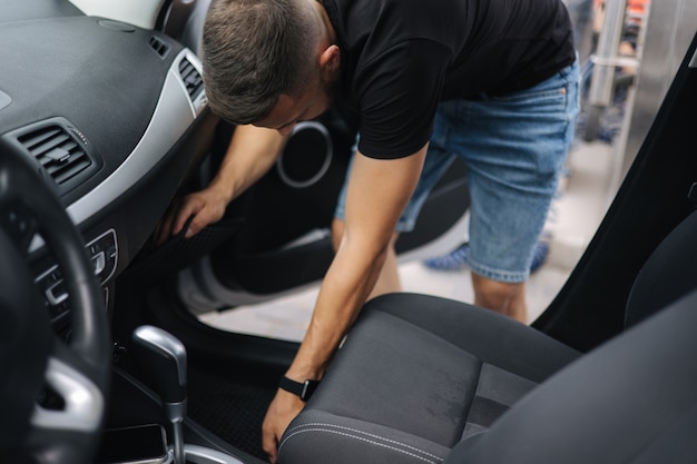 男は車からの自家洗車ビューで掃除のために車の前部座席を動かします