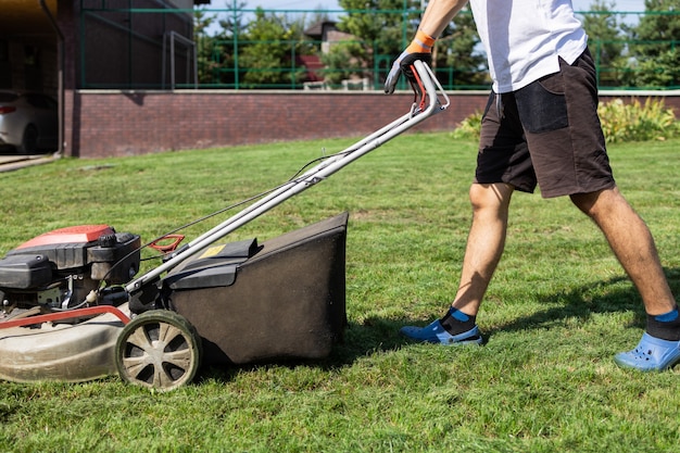 Man mowing the grass with gasoline lawn mower