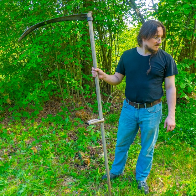 A man mows the grass with a authentic hand scythe