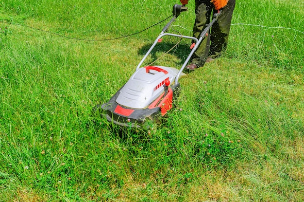 A man mows the grass with an electric lawn mower Freshly mown grass