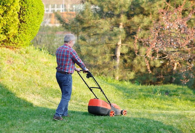 Man mows the lawn grass with a lawn mower.