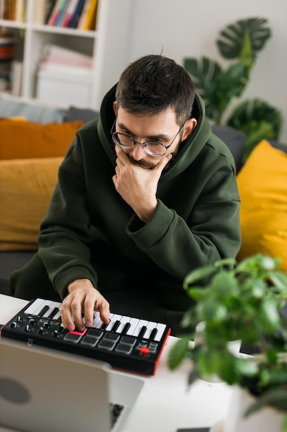 Man muziekproducent of arrangeur die laptop en midi-keyboard en andere audioapparatuur gebruikt om muziek te maken in de thuisstudio Beat maken en arrangeren van audio-inhoud en het componeren van songconcept