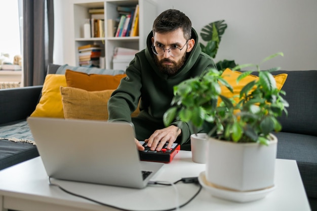 Man muziekproducent of arrangeur die laptop en midi-keyboard en andere audioapparatuur gebruikt om muziek te maken in de thuisstudio Beat maken en arrangeren van audio-inhoud en het componeren van songconcept