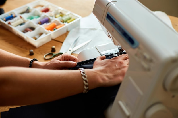 Man naait kleding op naaimachine mannelijke kleermaker werken met naaien in atelier textielindustrie hobby werkruimte kleine bedrijven creatieproces DIY werkplek van naaister