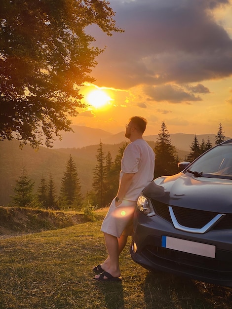 車の近くの男 山の夕日