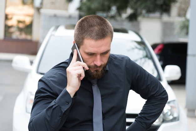 電話で話している車の近くの男