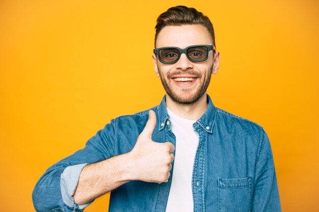 Un uomo vicino allo sfondo giallo con il pollice rivolto verso l'alto che racconta il suo umore fresco e il sorriso sul suo viso