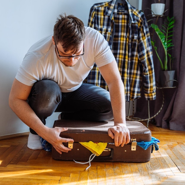 Man need help to close suitcase overloaded bag with clothes travel concept