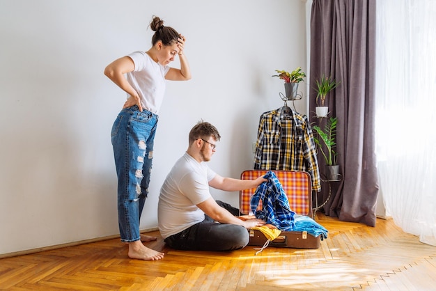 Man need woman help in packing travel concept man trying fit clothes in travel bag