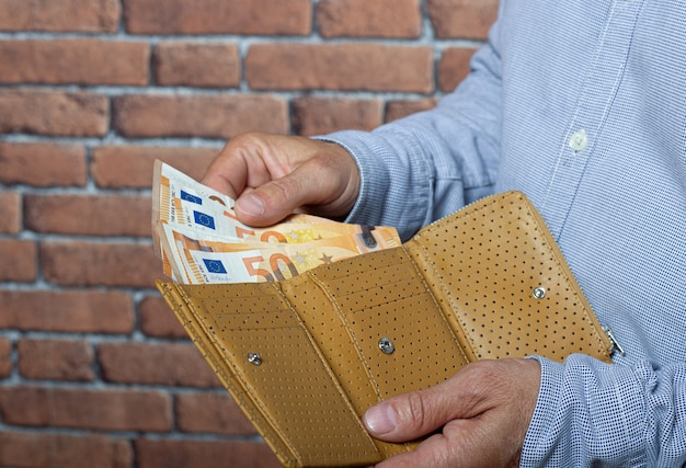 Man neemt euro geld uit zijn zakportemonnee.