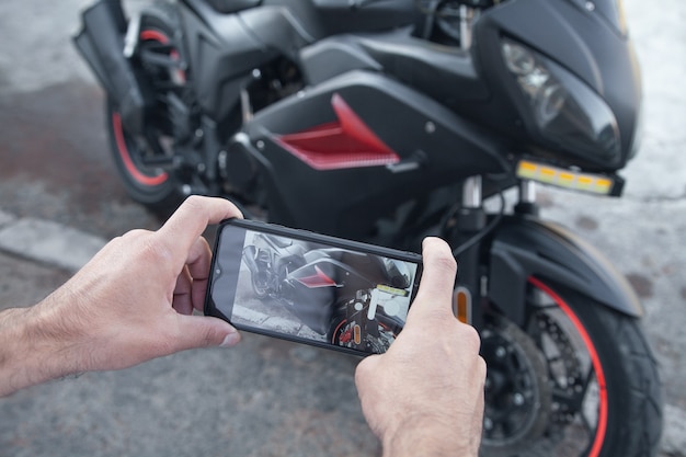 Man neemt foto van een motorfiets op zijn telefoon.