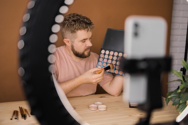 Man neemt videovlog op terwijl hij cosmetica aanbrengt of cosmetisch product verkent Guy maakt zelfstudie make-up voor zijn blog over cosmetica