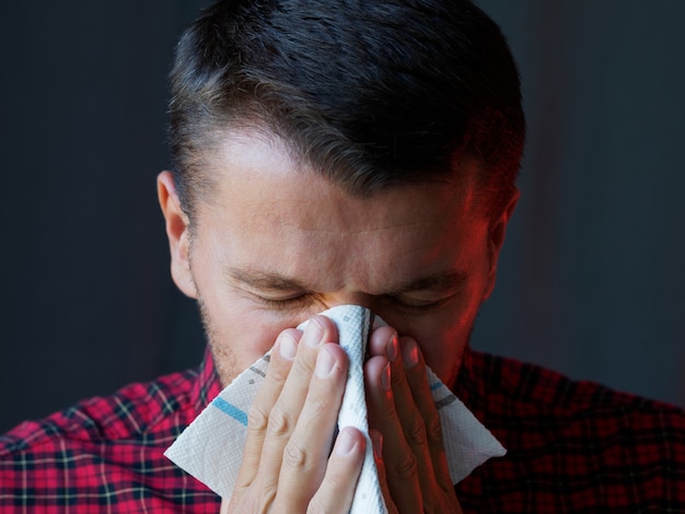 Man niezen gebruiken een servet. Voorzorgs- en preventiemethoden om de verspreiding van het pandemische virus te voorkomen.
