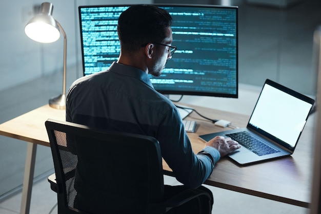 Man night and coding in office computer or blank screen for mockup space with html programming or web design Tech expert information technology or developer with typing laptop or dark workplace