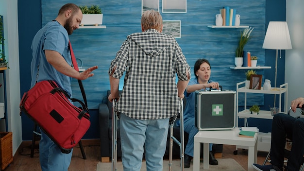 Man nurse supporting senior woman using walk frame