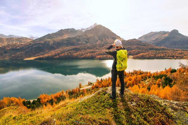 Man observes autumn landscape at a mountain lake