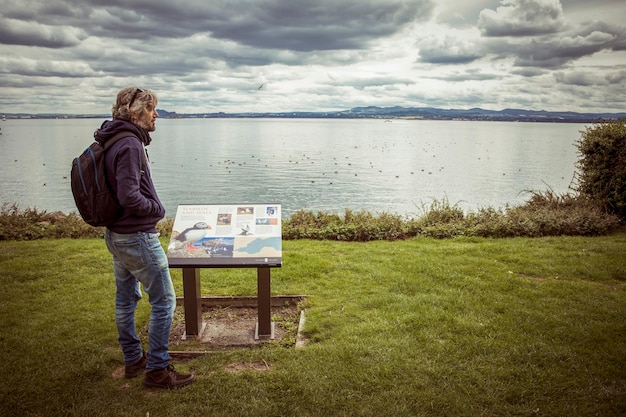 Foto l'uomo osserva gli uccelli marini davanti a un cartello
