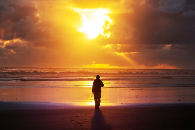 Man on ocean beach at sunset. Vacation concept background.