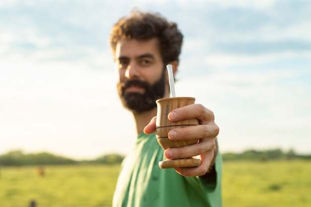 Man offering Argentinian mate at countryside in nature