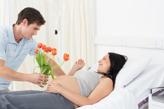 Man offering flowers to pregnant woman in hospital