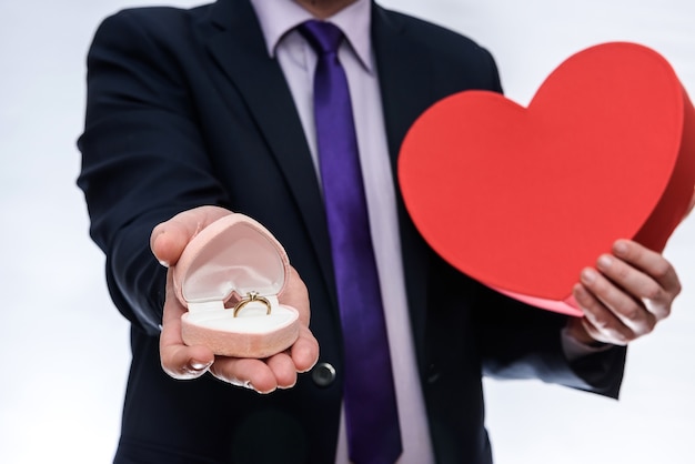 Man offering gift box with ring and red heart