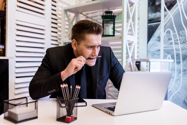 A man in the office bites a pencil