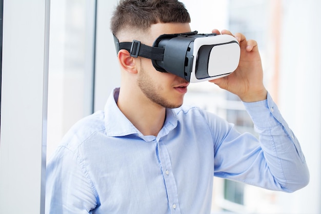 Man in office clothes and virtual reality glasses touching air